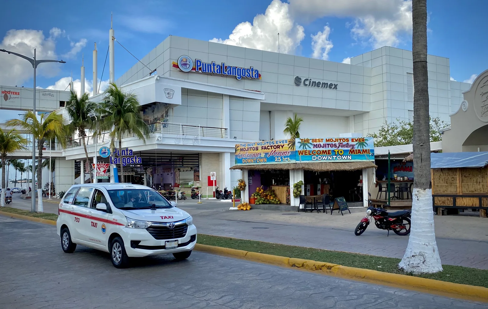 White and red taxi passing the Punta Langosta shopping complex in San Miguel de Cozumel
