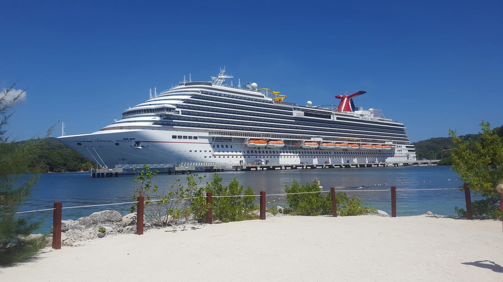 Carnival Breeze docked at Mahogany Bay on Roatán, viewed across the water from shore